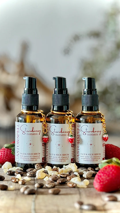 Three amber spray bottles labeled Strawberry Face & Neck Cream arranged on a wooden surface with scattered nuts and fresh strawberries around them.