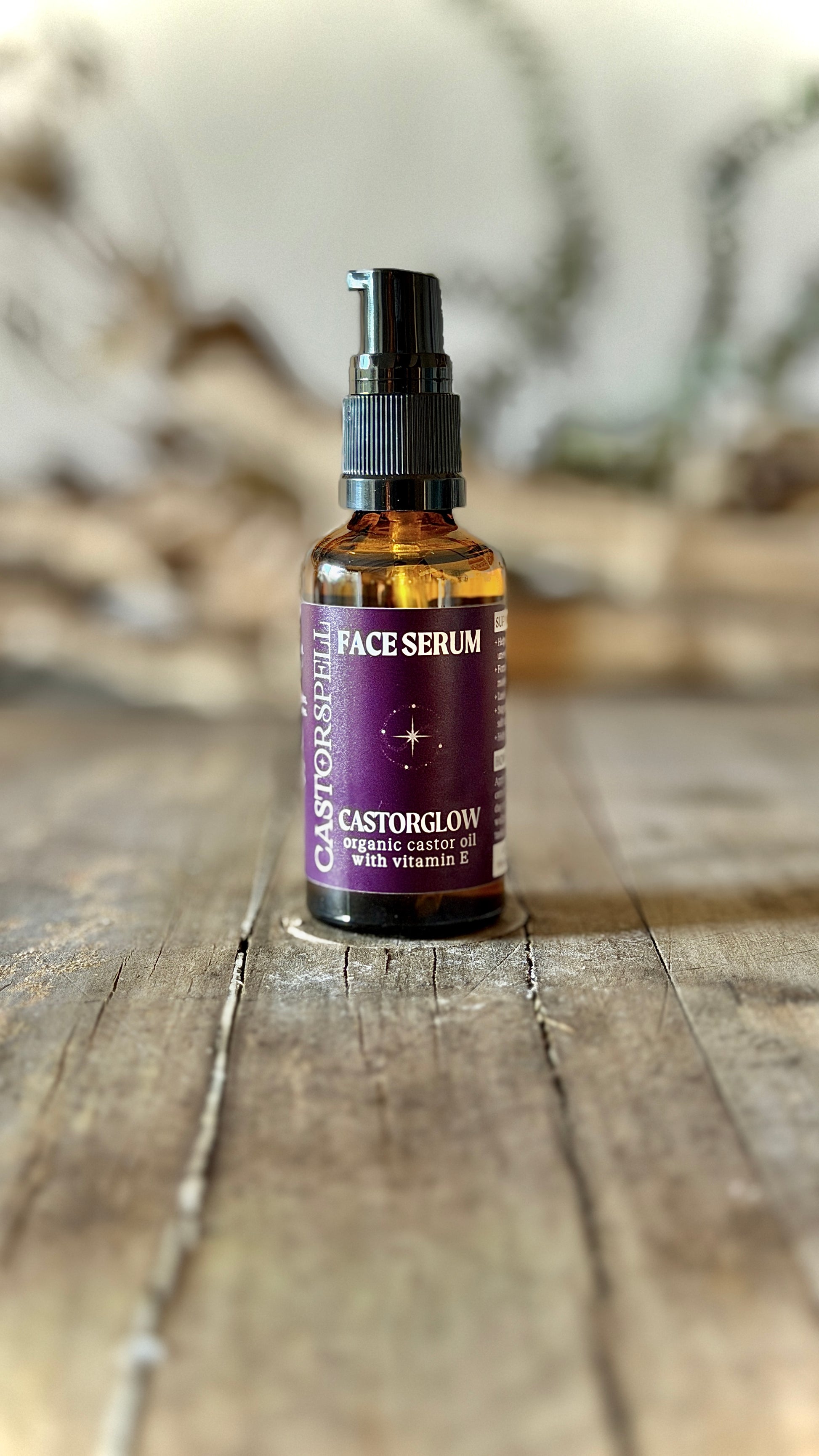 Bottle of face serum with a purple label on a wooden surface. Castor oil blen, organic, natural, low tox