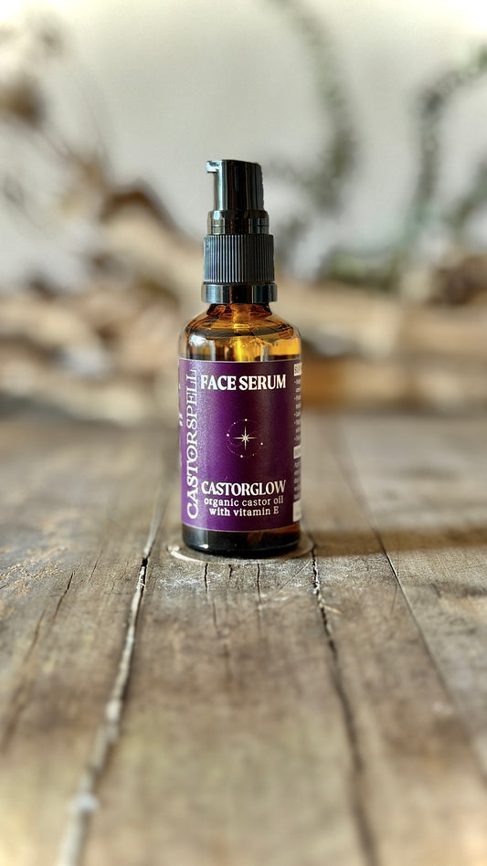 Bottle of face serum with a purple label on a wooden surface. Castor oil blen, organic, natural, low tox