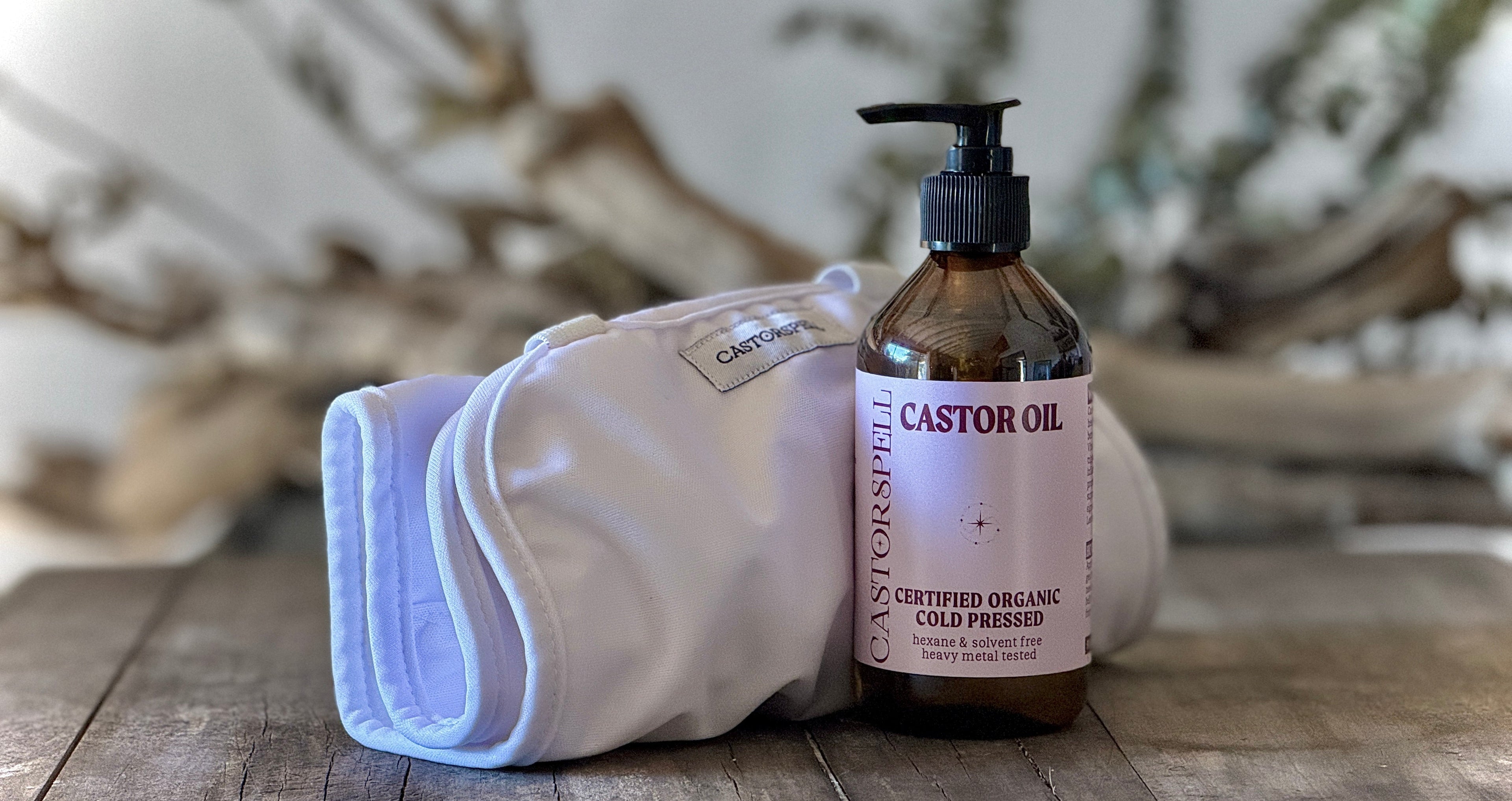 Bottle of Castor Oil with a Certified organic waist wrap, castor pack with pouch on a wooden surface